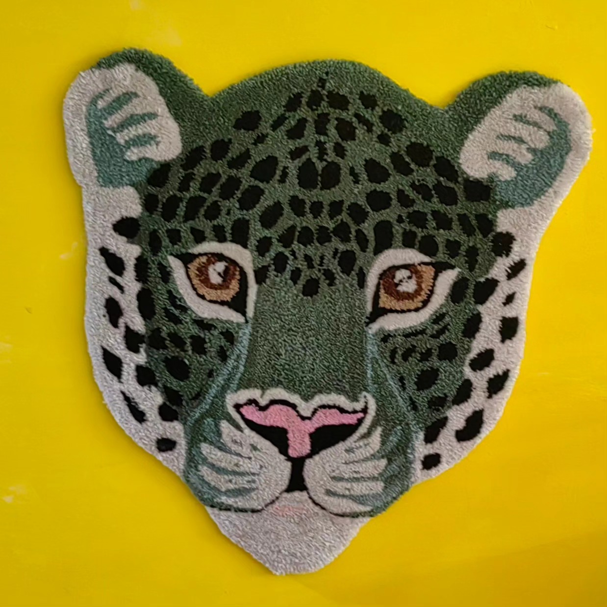 Sarı zemin üzerinde yeşil leopar başı desenli tufting çalışması